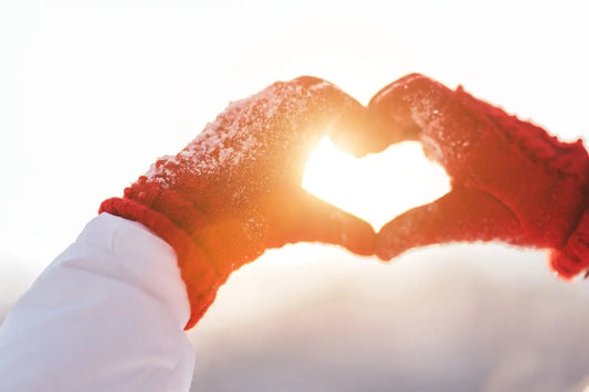 Gloves making a heart shape with sun shining through